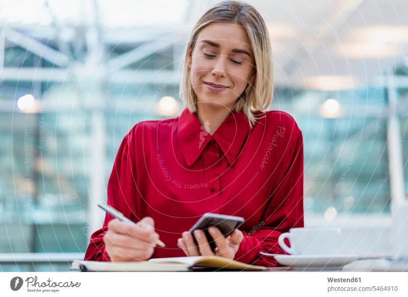 Young businesswoman with cell phone taking notes in a cafe Occupation Work job jobs profession professional occupation business life business world