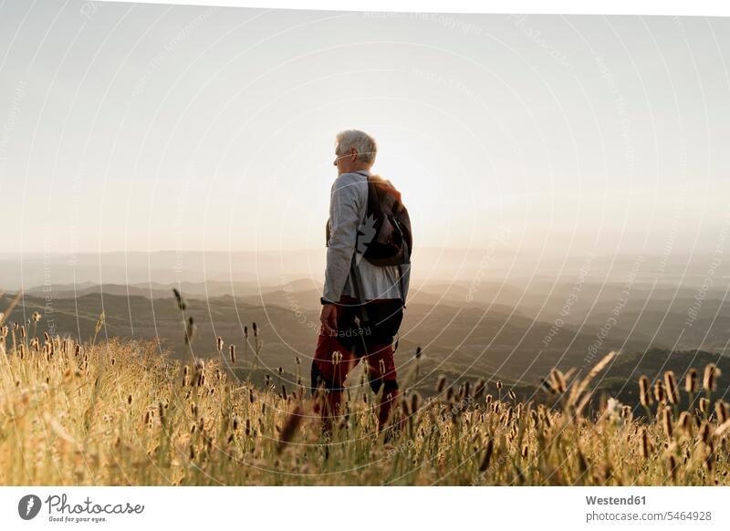 Active senior male hiker standing on mountain while looking at landscape during sunset color image colour image Spain outdoors location shots outdoor shot