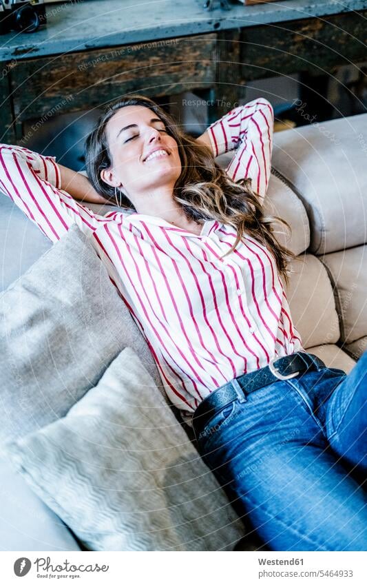 Smiling relaxed woman lying on couch females women relaxation settee sofa sofas couches settees laying down lie lying down Adults grown-ups grownups adult