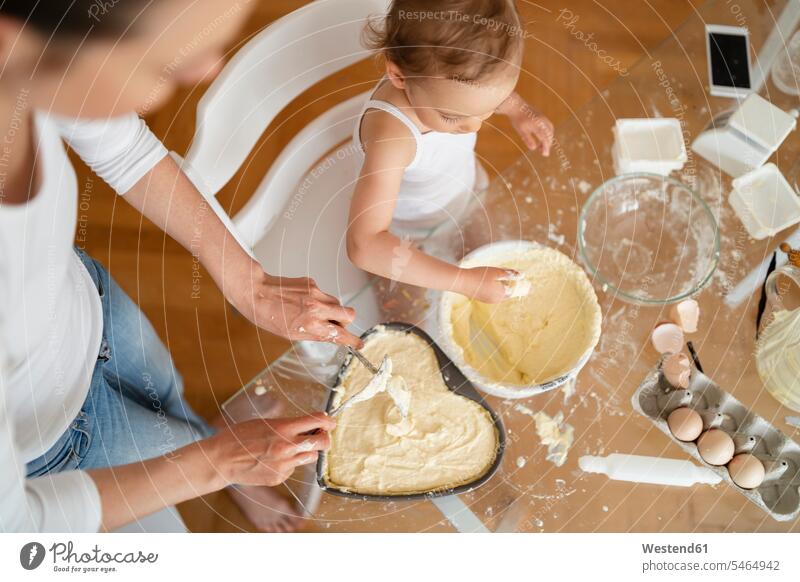 Top view of mother and little daughter making a cake together in kitchen at home pies cakes domestic kitchen kitchens mommy mothers mummy mama daughters baking