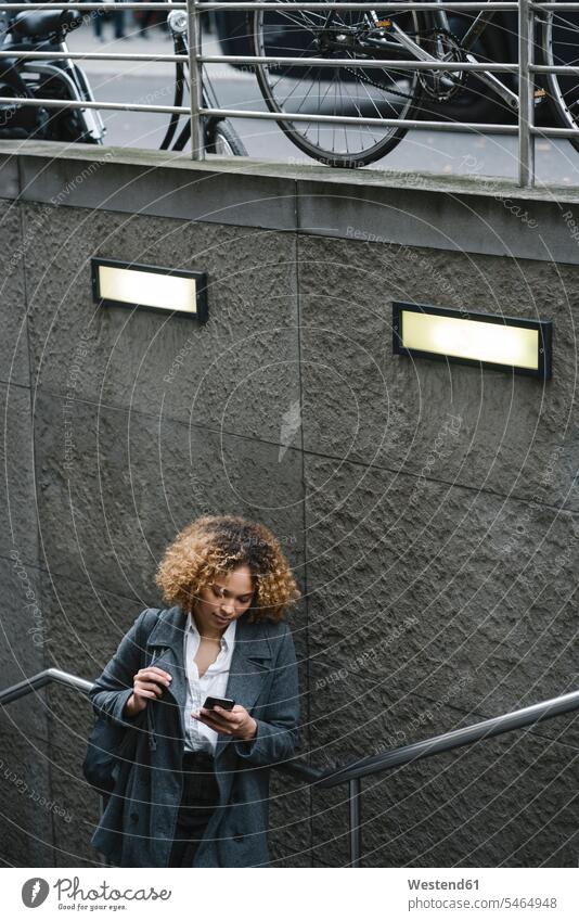Woman using smartphone at the entrance of a subway station, Berlin, Germany business life business world business person businesspeople business woman