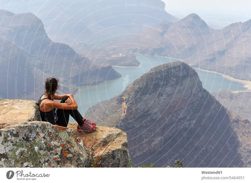 Woman sitting on a rock with beautiful landscape as background, Blyde River Canyon, South Africa human human being human beings humans person persons adult
