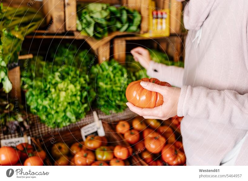 Woman choosing and picking fresh vegetables from grocery store color image colour image indoors indoor shot indoor shots interior interior view Interiors day