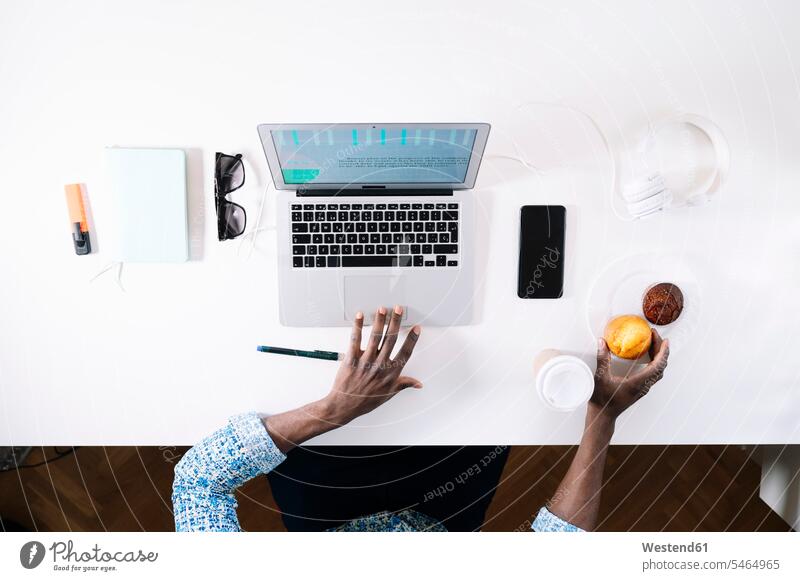 Man taking muffin while working at home color image colour image indoors indoor shot indoor shots interior interior view Interiors Spain Home Interior