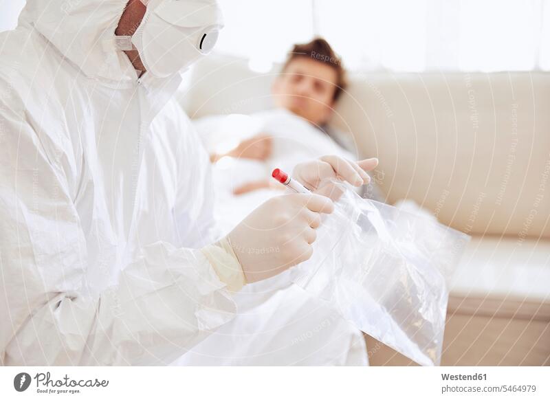 Close-up of doctor holding medical sample in plastic bag while patient resting on sofa color image colour image Germany indoors indoor shot indoor shots