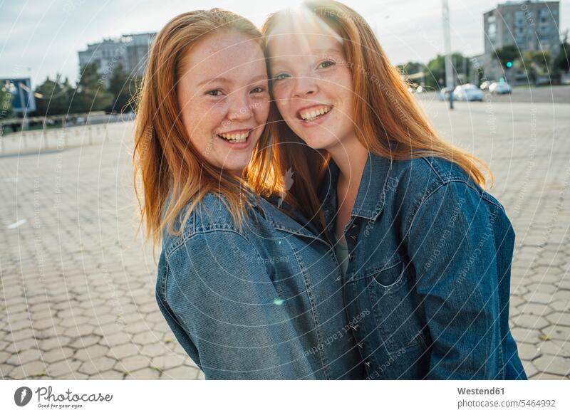 Smiling redheaded twins in the city, sunlight sister sisters long hair longhair long-haired red hair red hairs red-haired equality woman females women siblings