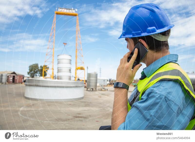 Man in workwear on construction site talking on cell phone working clothes man men males mobile phone mobiles mobile phones Cellphone cell phones Building Site