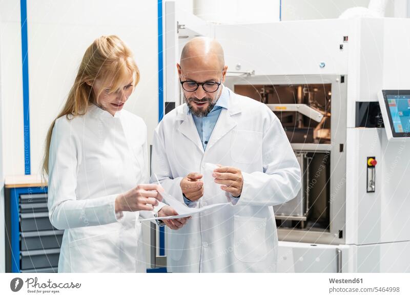 Two technicians wearing lab coats discussing plan plans discussion Laboratory Coat Labcoats Lab Coat Laboratory Coats Lab Coats looking eyeing view seeing