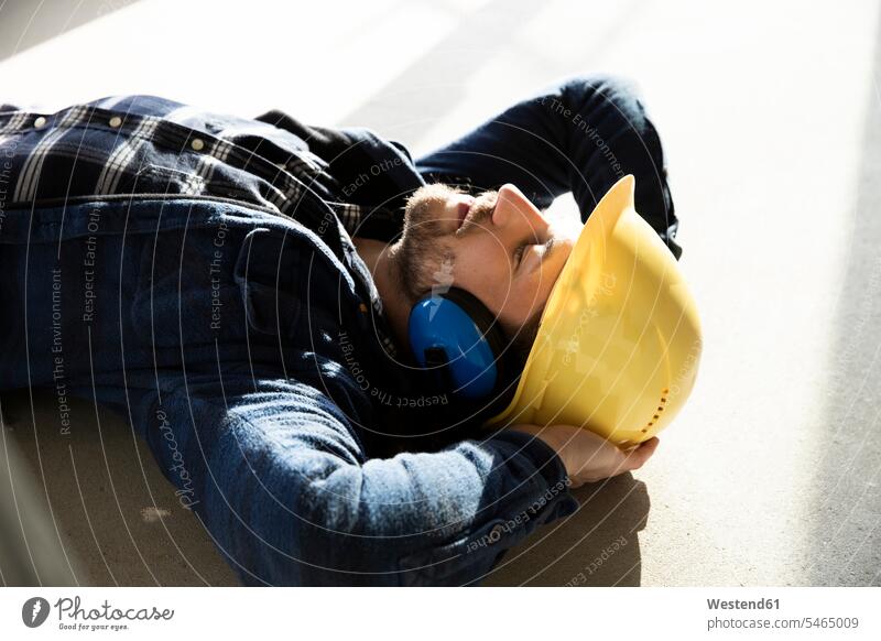 Close-up of construction worker with hands behind head sleeping on floor in renovating house color image colour image Germany Architecture construction site