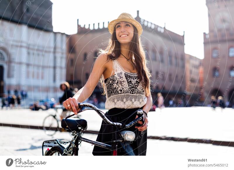 Italy, Bologna, portrait of fashionable young woman pushing bicycle in the city bikes bicycles portraits smiling smile females women town cities towns Adults