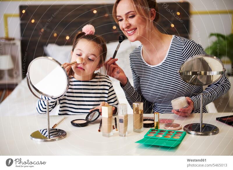 Mother and daughter applying make up together Fun having fun funny Makeup Make-up Paint sitting Seated vanity dressing table vanity table vanity counter