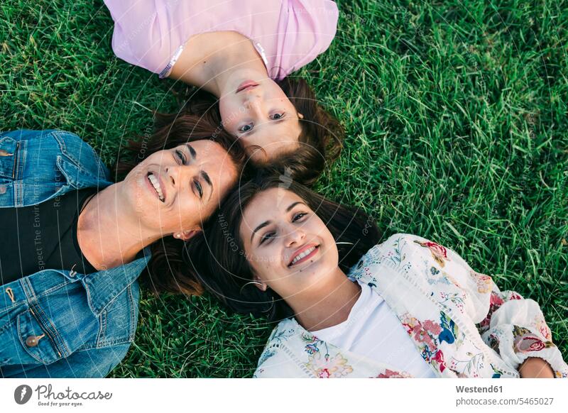 Smiling mother with daughters lying on grassy land in park color image colour image Portugal leisure activity leisure activities free time leisure time