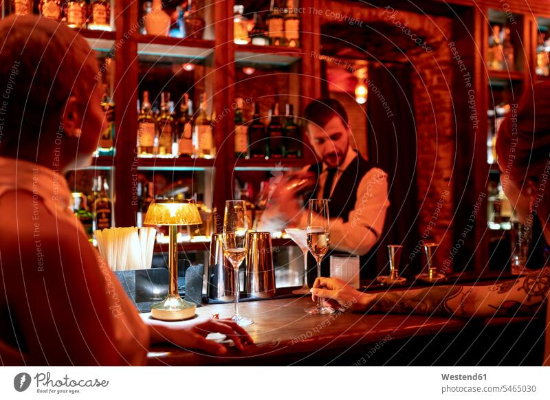 Bartender mixing cocktail while standing at bar counter in pub color image colour image indoors indoor shot indoor shots interior interior view Interiors