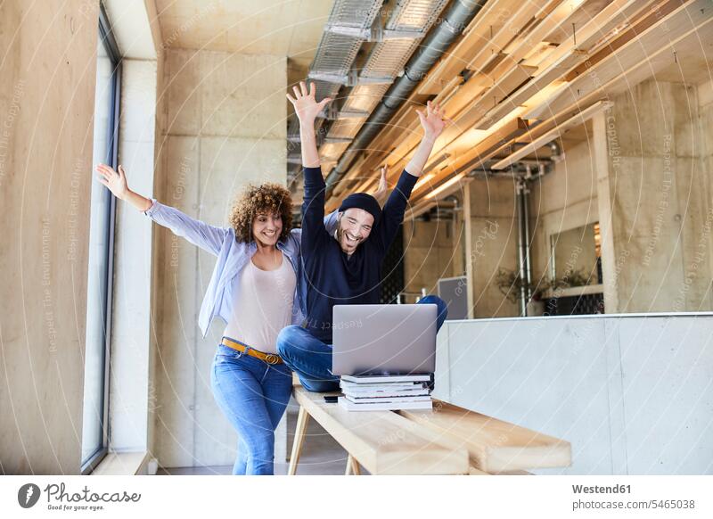 Excited man and woman with laptop in modern office freelancer freelancing Germany break room businesswoman businesswomen business woman business women Internet