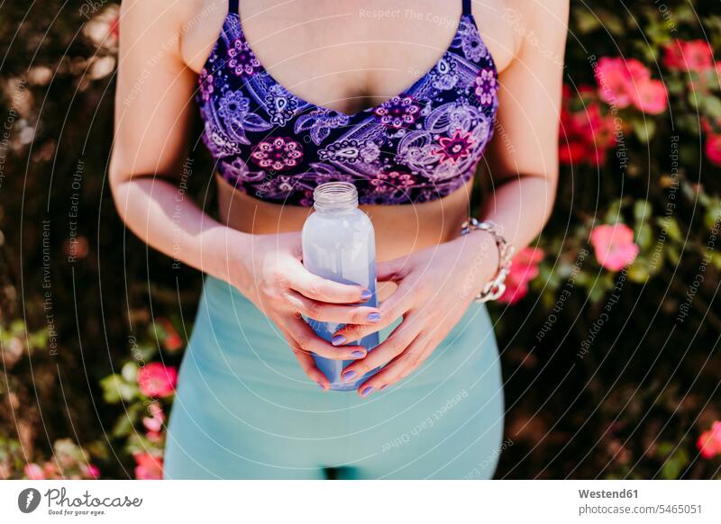 Sporty woman holding water bottle in park color image colour image outdoors location shots outdoor shot outdoor shots day daylight shot daylight shots day shots