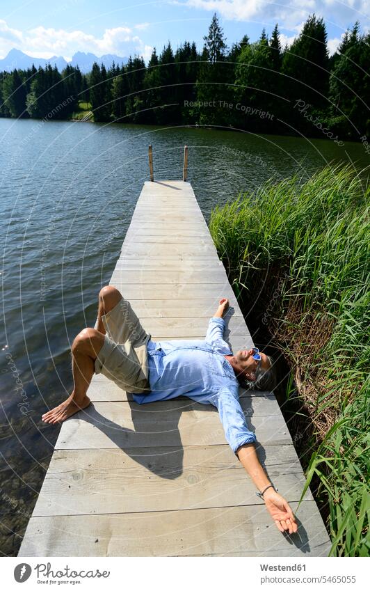 Germany, Mittenwald, mature man lying on jetty at lake relaxing landing stage landing stages laying down lie lying down relaxation men males lakes Adults