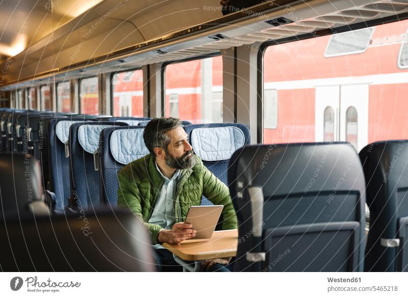 Man sitting in train holding tablet Occupation Work job jobs profession professional occupation business life business world business person businesspeople
