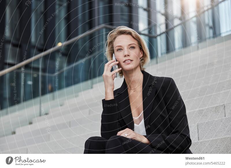 Portrait of young businesswoman on the phone sitting on stairs outdoors businesswomen business woman business women portrait portraits call telephoning