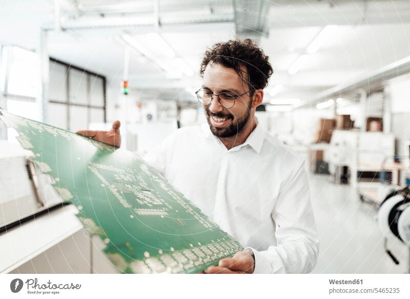Smiling male technician analyzing large computer chip in industry color image colour image Germany indoors indoor shot indoor shots interior interior view