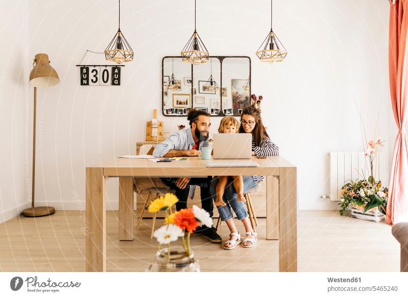 Parents with daughter using laptop on dining table at home color image colour image indoors indoor shot indoor shots interior interior view Interiors