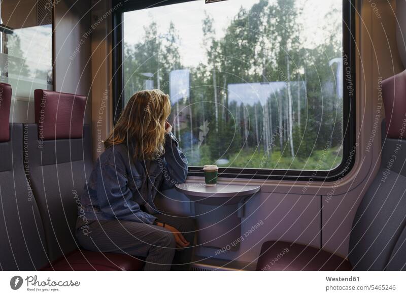 Woman traveling by train looking out of window travelling view seeing viewing windows woman females women Adults grown-ups grownups adult people persons