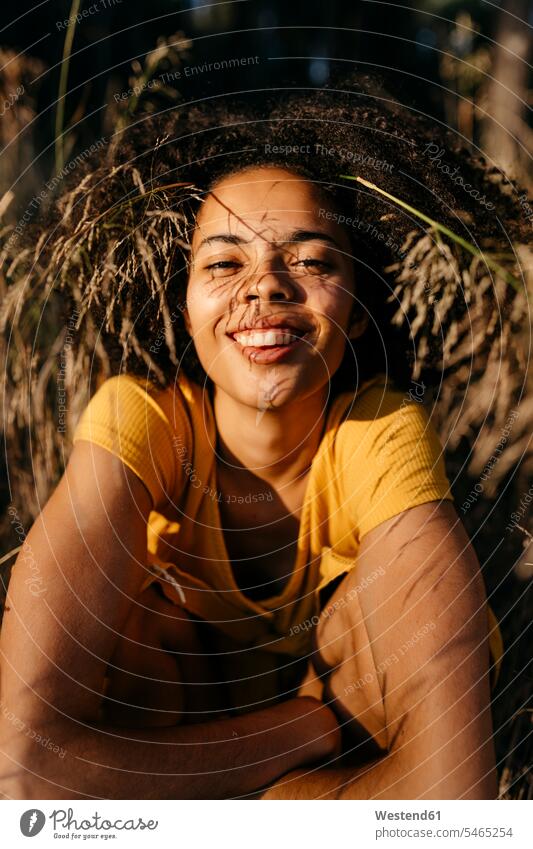 Close-up of smiling young woman with afro hair sitting in forest color image colour image Spain leisure activity leisure activities free time leisure time