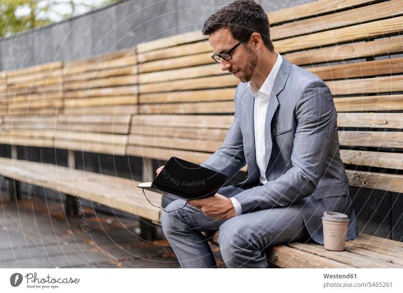 Businessman sitting on wooden bench in the city writing into notebook business life business world business person businesspeople Business man Business men