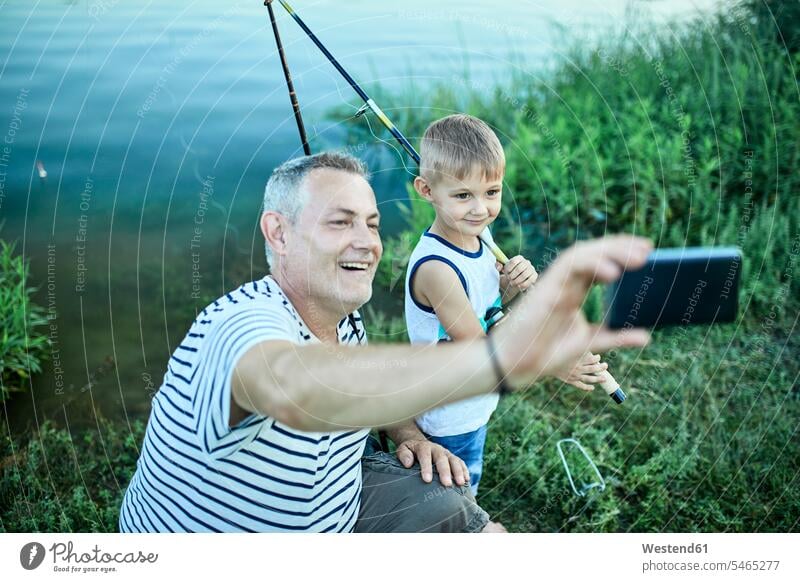 Grandfather and grandson taking selfie with smartphone at lakeshore Smartphone iPhone Smartphones grandfather grandpas granddads grandfathers Lakeshore