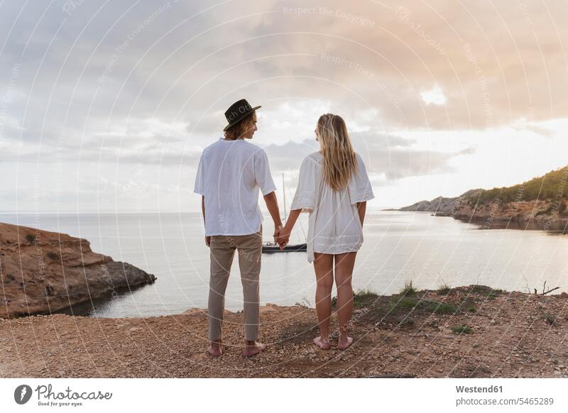 Back view of young couple in love standing in front of the sea, Ibiza, Balearic Islands, Spain human human being human beings humans person persons