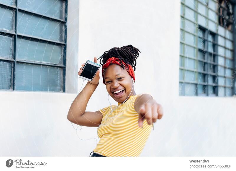 Portrait of excited young woman listening music with headphones and earphones in front of white wall human human being human beings humans person persons