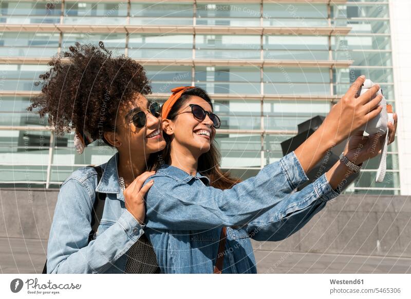 Smiling friends taking selfie though camera while standing at rooftop color image colour image day daylight shot daylight shots day shots daytime friendship