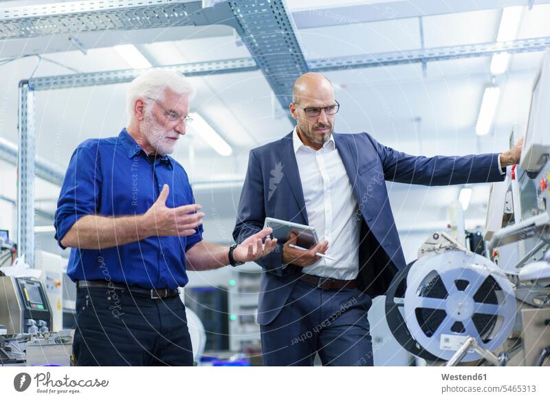 Confident male colleagues discussing while looking at machinery in laboratory color image colour image indoors indoor shot indoor shots interior interior view