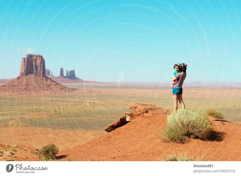 USA, Utah, Monument Valley, Mother traveling with baby girl, mother carrying girl, standing on viewpoint Looking At View Looking at a view Wanderlust Itchy Feet