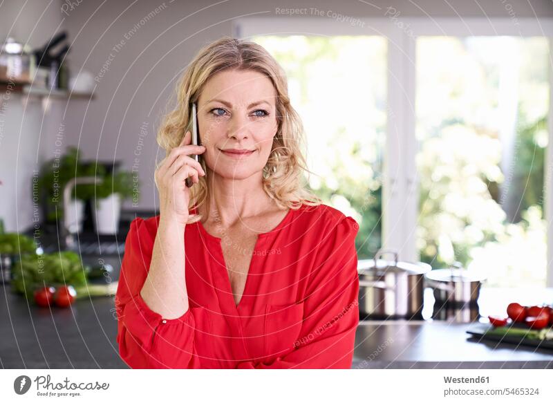 Portrait of smiling woman on the phone in kitchen call telephoning On The Telephone calling females women portrait portraits domestic kitchen kitchens smile