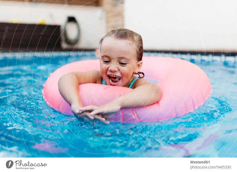 Portrait of little girl with floating tire in pool floating tires floating tyre floating tyres seasons summer time summertime summery delight enjoyment Pleasant