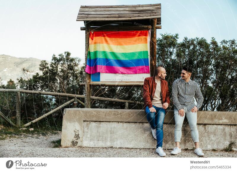 Gay couple with gay pride flag on a trip in the mountains human human being human beings humans person persons caucasian appearance caucasian ethnicity european
