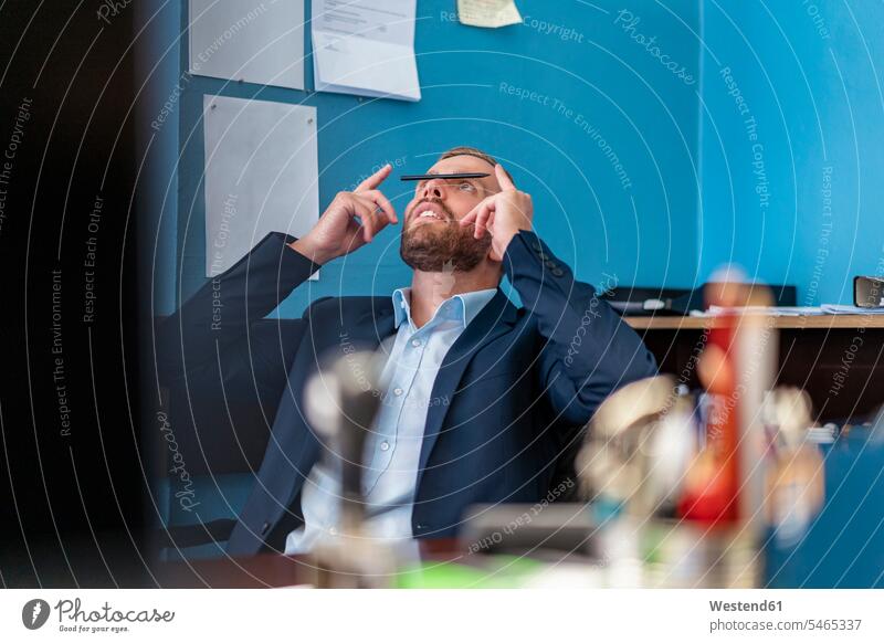 Businessman at desk in office balancing a pen on his nose human human being human beings humans person persons caucasian appearance caucasian ethnicity european