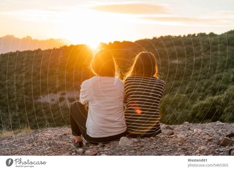 Friends watching sunset from a mountain looking looking at sunsets sundown female friends mountains view seeing viewing atmosphere atmospheric mood moody