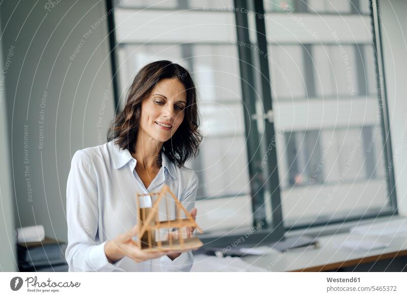 Businesswoman holding architectural model of a house office offices office room office rooms female architect architects female architects Architectural Model