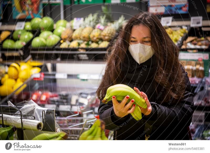 Mature woman buying bananas while grocery shopping during COVID-19 color image colour image indoors indoor shot indoor shots interior interior view Interiors