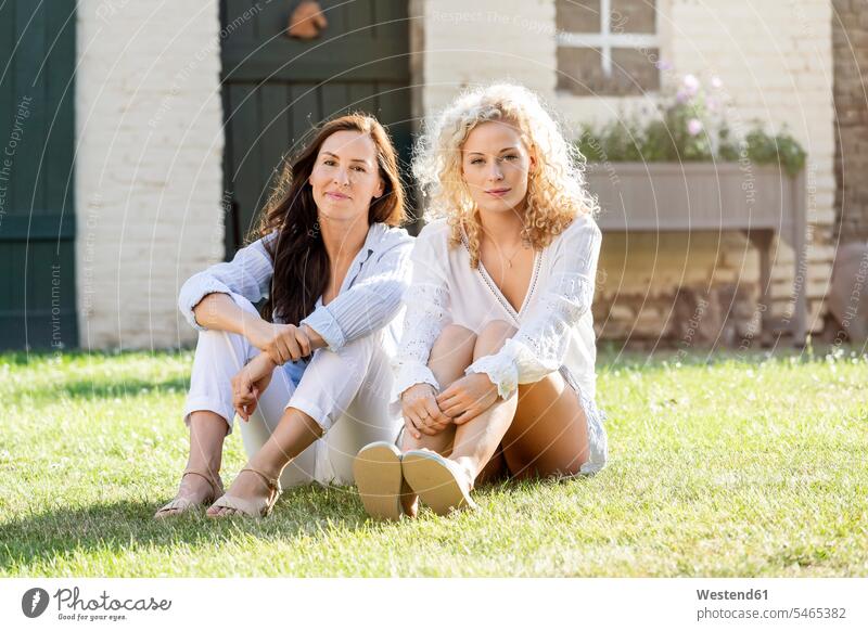 Two women sitting in the garden on grass in the sunshine female friends bonding community Companionship confidence confident togetherness Grassy nature