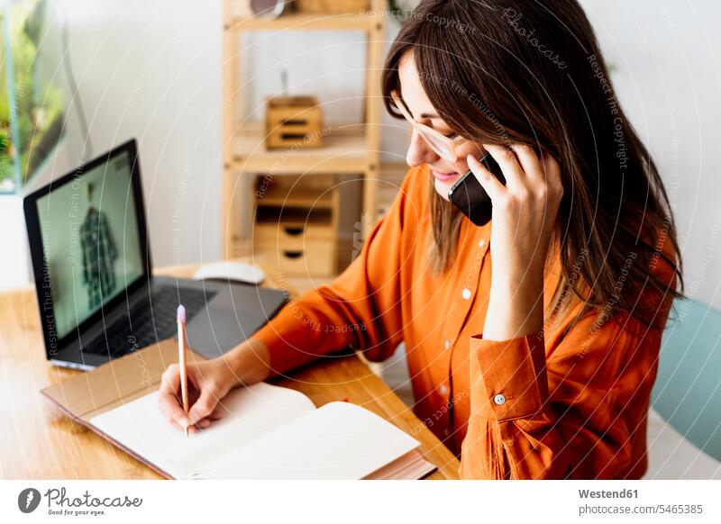 Female fashion designer working at home sitting at desk taking notes Occupation Work job jobs profession professional occupation business life business world