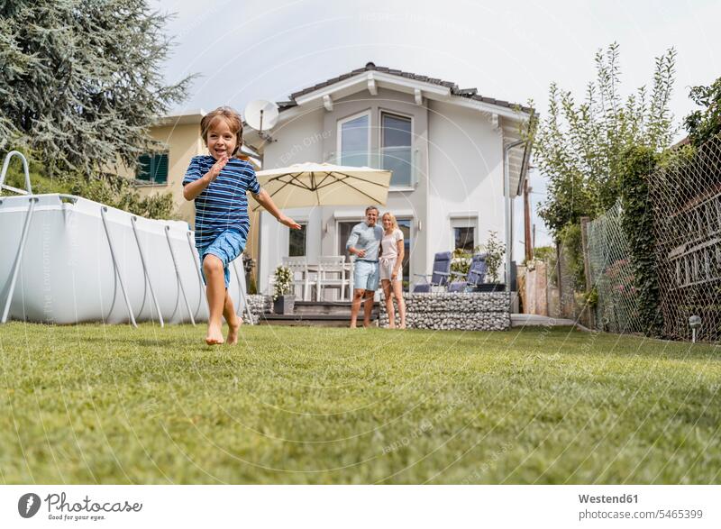 Boy running in garden with parents watching T- Shirt t-shirts tee-shirt play summer time summertime summery Ardor Ardour enthusiasm enthusiastic excited delight