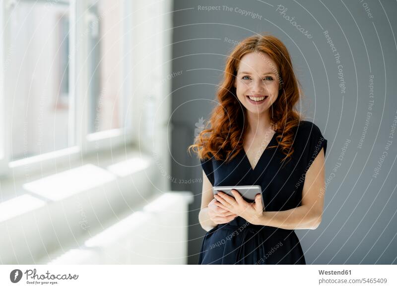 Portrait of content redheaded businesswoman with digital tablet in a loft human human being human beings humans person persons caucasian appearance
