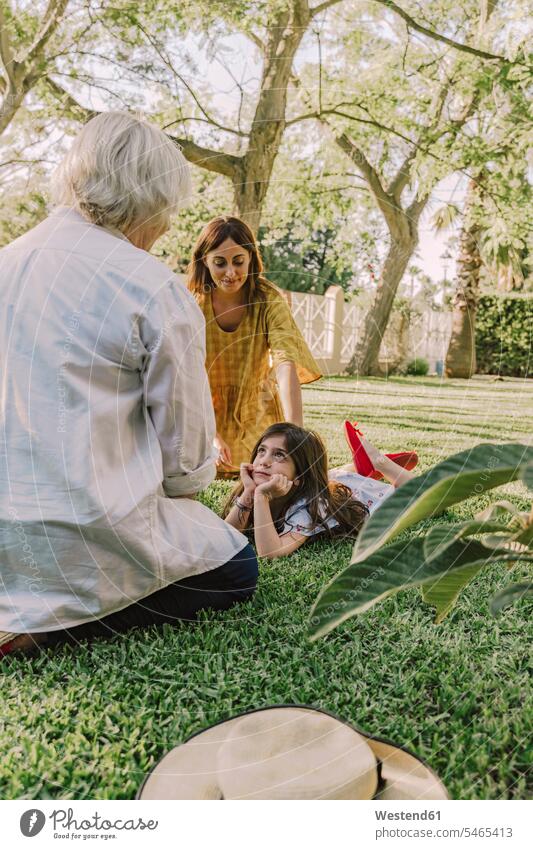 Multi-generation family relaxing on grassy land in yard color image colour image Spain leisure activity leisure activities free time leisure time