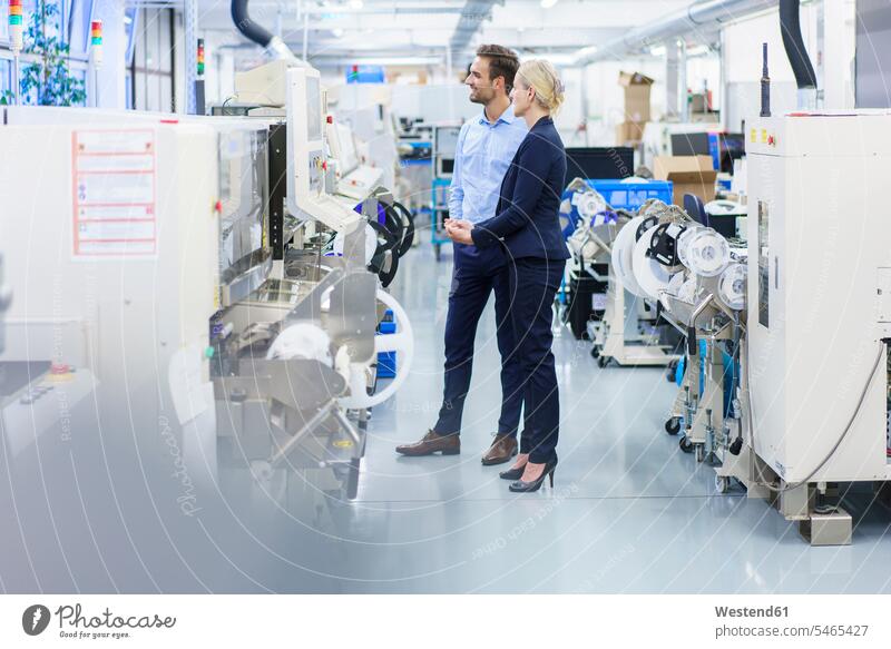 Businesswoman and businessman looking at machinery in illuminated industry color image colour image indoors indoor shot indoor shots interior interior view