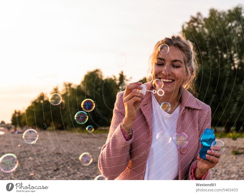 Laughing blond woman and soap bubbles laughing Laughter Fun having fun funny females women blowing hovering floating happiness happy positive Emotion Feeling