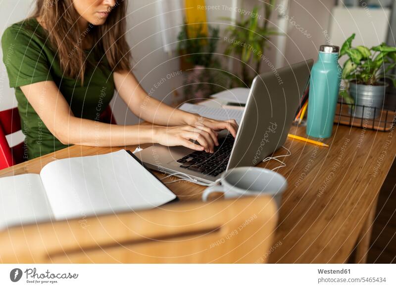 Businesswoman using laptop on desk while sitting in home office color image colour image Spain casual clothing casual wear leisure wear casual clothes