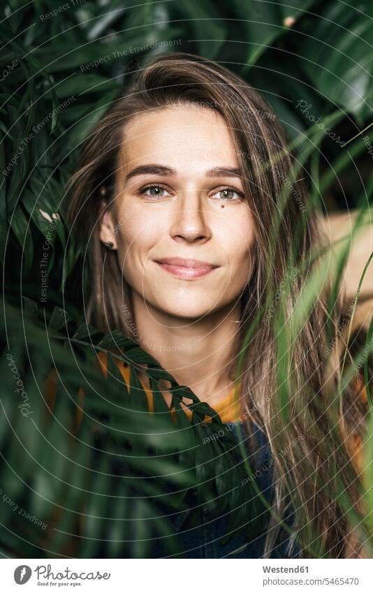 Portrait of a young woman amidst green plants heads faces human face human faces smile passionate Contented Emotion pleased colour colours horticulture