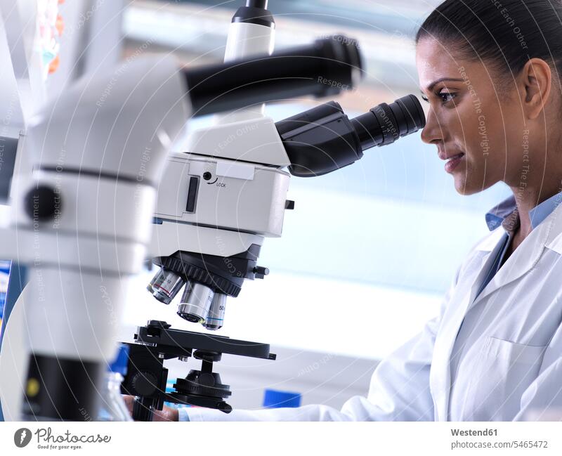 Biotechnology Research, female scientist examining a specimen under a microscope in the laboratory experiment experimenting trials specimens female researcher